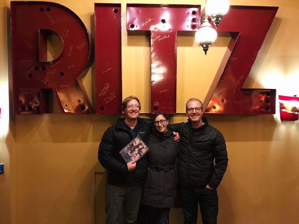 Three people standing in front of the letters "Ritz" in the entryway of the Ritz Theater