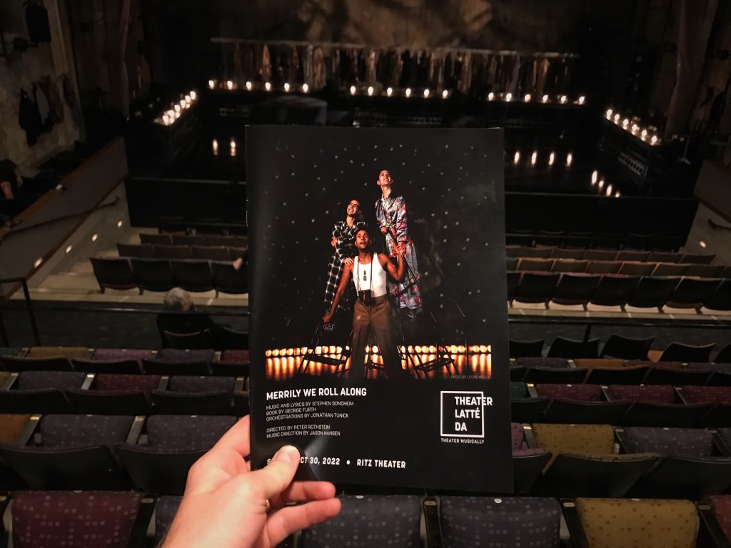A hand holding a program for heater Latté Da's production of "Merrily We Roll Along," the 1981 Stephen Sondheim show, playing at the Ritz Theater in Minneapolis through October 30