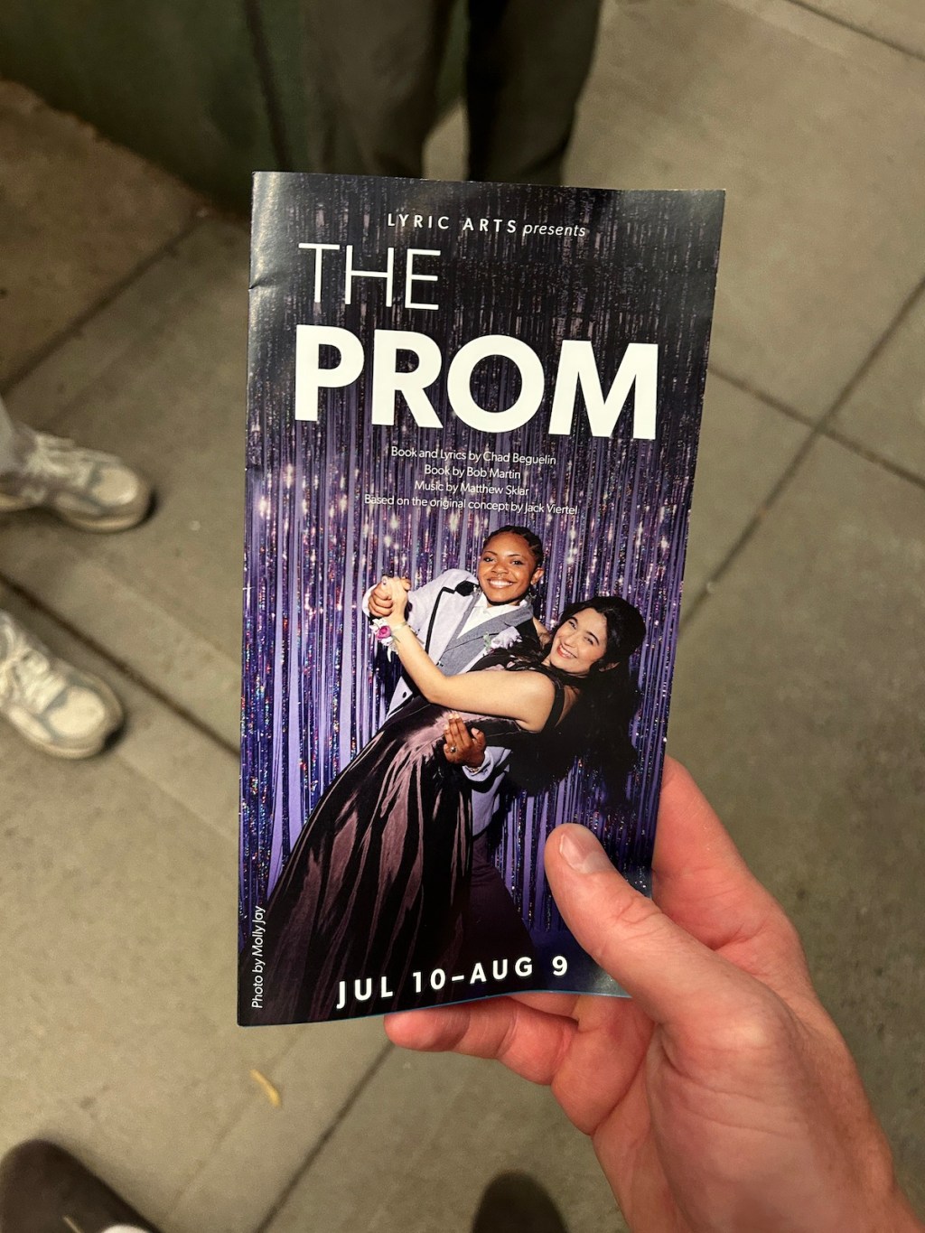 A hand holding a purple program for the musical "The Prom" at Lyric Arts in Anoka